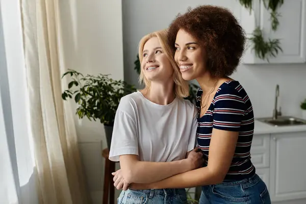 A lesbian couple stands in their kitchen, their body language suggesting an understanding. — Stock Photo