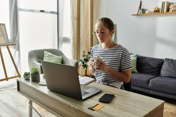 Eine junge Frau genießt einen ruhigen Moment mit einem warmen Getränk an ihrem Schreibtisch. — Stock Photo