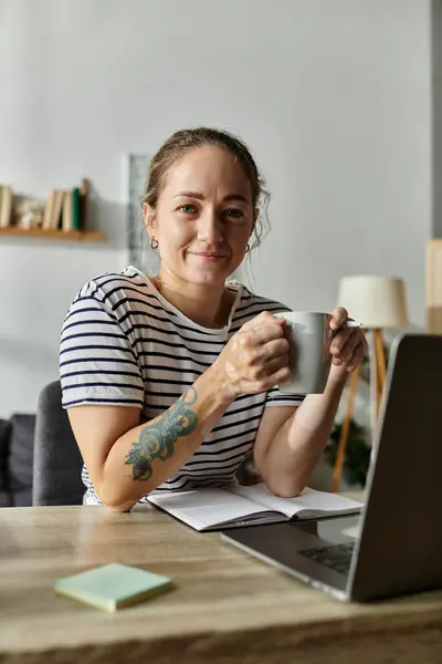 A young woman smiles while holding a warm mug in her stylish workspace. — Stock Photo