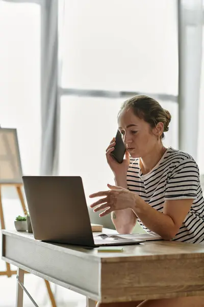 A woman with vitiligo speaks on the phone while working at her desk. — Stock Photo