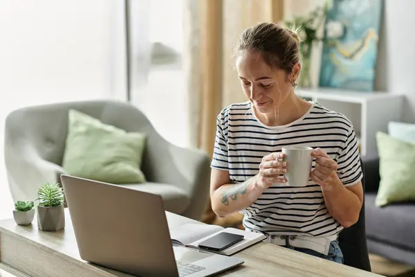 A woman with vitiligo relaxes with a warm drink while working at her desk. — Stock Photo