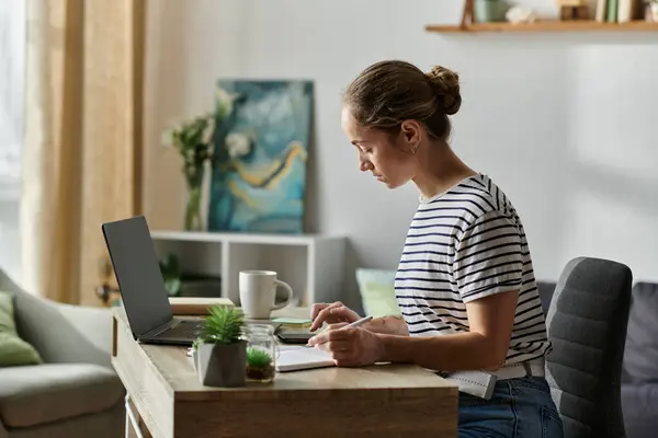 A young woman studies attentively at her stylish desk filled with plants. — Stock Photo