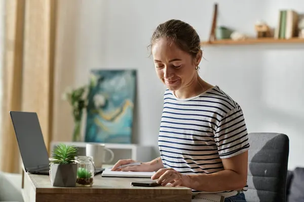A young woman with vitiligo smiles while focusing on her work at a cozy desk. — Stock Photo