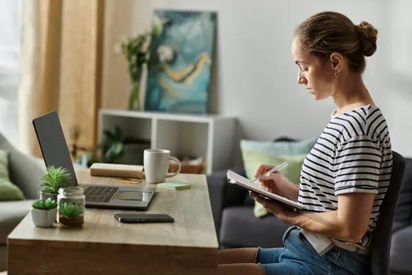 Una donna con vitiligine si concentra intensamente mentre scrive nel suo quaderno. — Foto stock