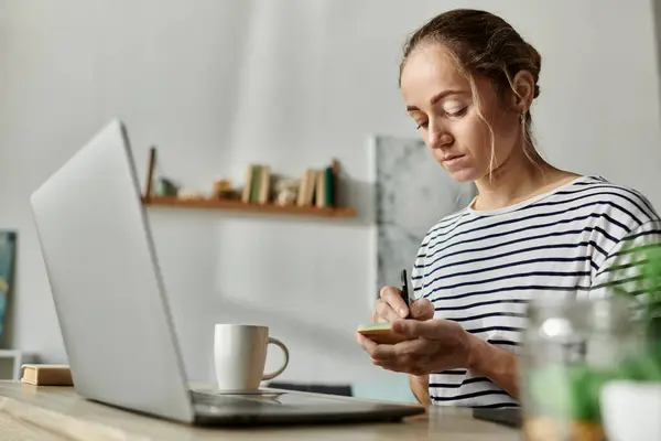 Una donna con la vitiligine si concentra sulla scrittura di note alla sua scrivania. — Foto stock