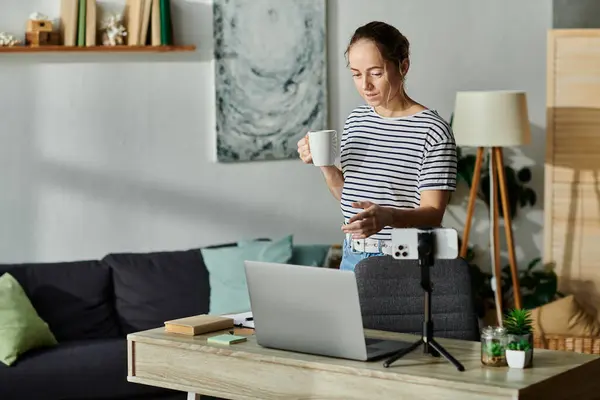 A young woman with vitiligo enjoys her morning coffee while focused on her work. — Stock Photo