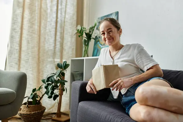 A joyful woman sits comfortably, embracing her unique beauty in a cozy space. — Stock Photo