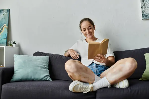 A woman with vitiligo smiles while enjoying a book in a comfortable setting. — Stock Photo