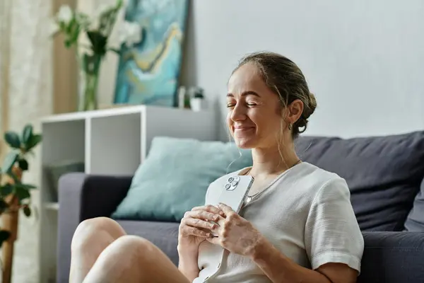A woman with vitiligo smiles contentedly while holding her phone close. — Stock Photo