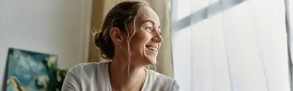 A joyful woman with vitiligo smiles brightly by the window. — Stock Photo
