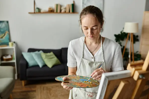 A beautiful woman expresses her creativity with vibrant paints in a warm space. — Stock Photo