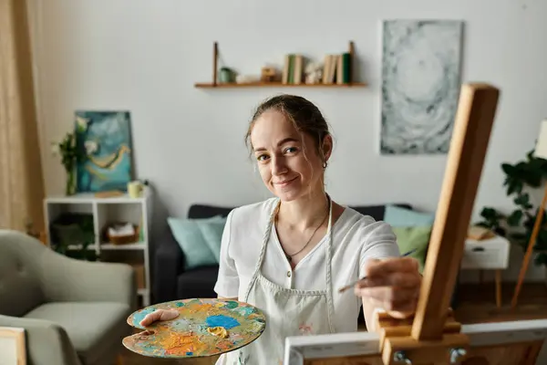 A talented woman with vitiligo smiles while painting on a canvas. — Stock Photo