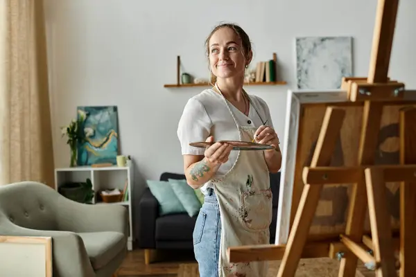 Una mujer alegre con vitiligo pinta felizmente sobre lienzo en su acogedor estudio. — Stock Photo