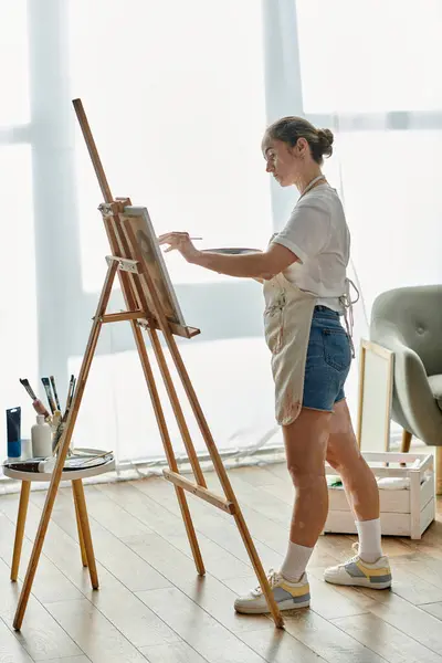 A woman with vitiligo passionately paints in a sunny studio. — Stock Photo