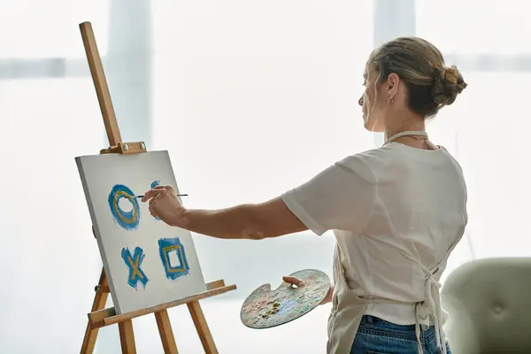 A young woman with vitiligo creates vibrant art in soft, natural light. — Stock Photo