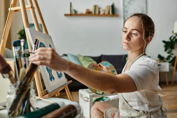 A woman with vitiligo creates art on canvas, surrounded by an inviting studio atmosphere. — Stock Photo