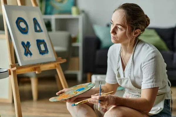 A woman explores her creativity through painting in a warm, inviting studio. — Stock Photo