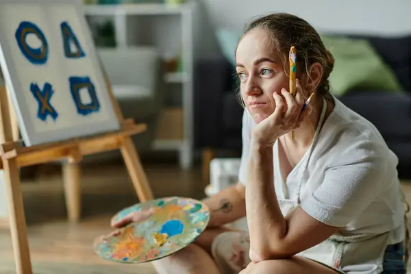 A young woman with vitiligo thoughtfully engages in her art at home. — Stock Photo