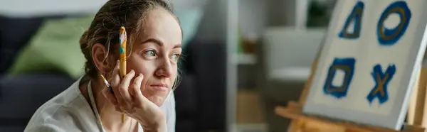 Una mujer con vitiligo contempla pensativamente su creación artística. - foto de stock