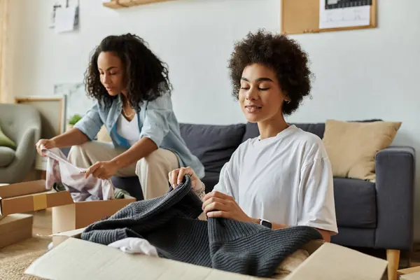 Pareja alegre transforma la ropa vieja en nuevas y elegantes piezas en su vibrante hogar. - foto de stock