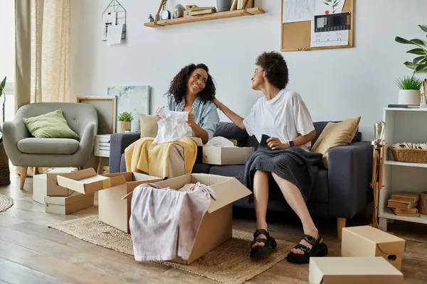 Lgbt couple joyfully upcycling clothes while surrounded by cardboard boxes. — Stock Photo