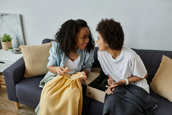 Couple remontant joyeusement leurs vêtements tout en partageant des sourires dans un cadre confortable. — Photo de stock