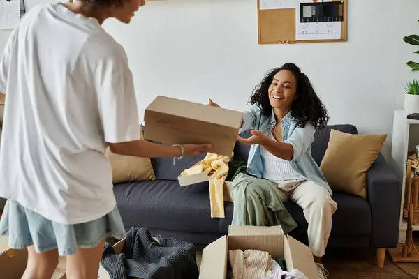 Couple joyfully shares clothes while upcycling in their stylish living room. — Stock Photo