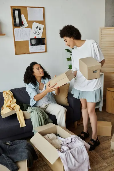 A couple joyfully sorts through boxes of clothes for upcycling. — Stock Photo