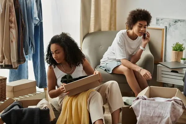 Two partners joyfully repurposing old clothes in their stylish living space. — Stock Photo