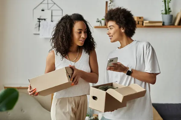 Una coppia esalta gioiosamente il loro guardaroba attraverso progetti di upcycling, scatola in mano. — Foto stock