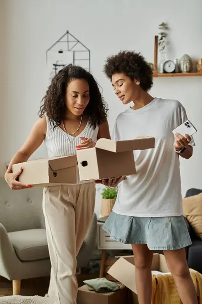 Una pareja transforma alegremente la ropa vieja en nuevos estilos juntos, caja en las manos. - foto de stock