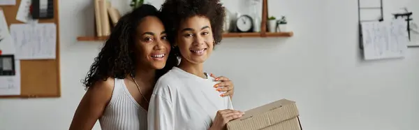 Two partners joyfully repurpose their clothing in a creative workspace, box in hands. — Stock Photo