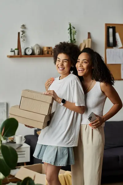 LGBT couple smiles while upcycling their clothes in a stylish home space, box in hands. — Stock Photo