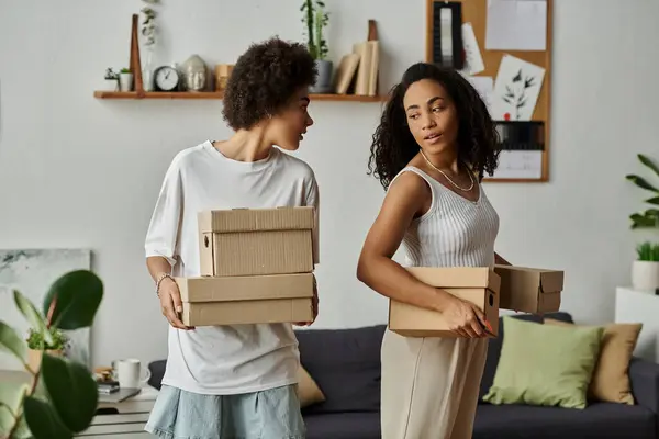 Lgbt casal alegremente upcycling suas roupas em uma sala de estar aconchegante, caixas nas mãos. — Fotografia de Stock