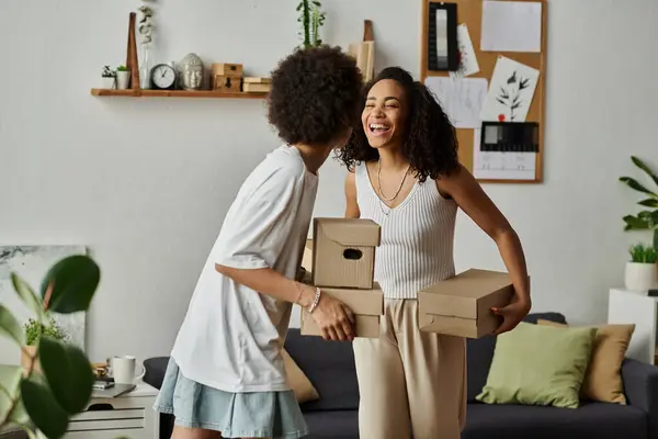 Casal organiza alegremente caixas enquanto upcycling seu guarda-roupa juntos, caixas nas mãos. — Fotografia de Stock