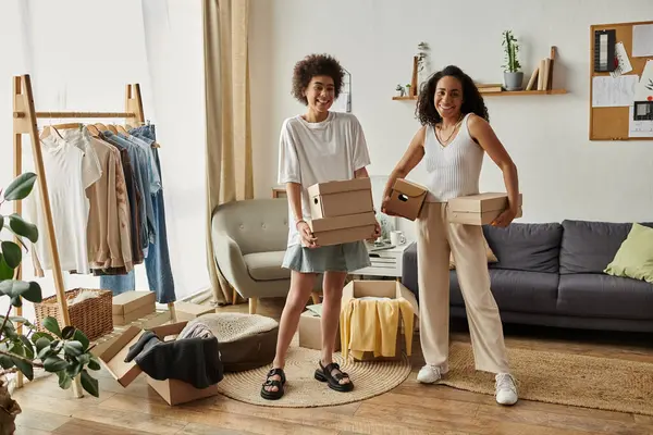 Couple joyfully transforms old garments into stylish pieces in their vibrant home, boxes in hands. — Stock Photo
