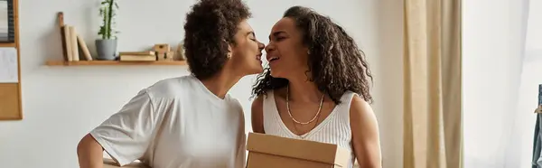 Dos socios comparten un momento mientras que upcycling ropa juntos, caja de espera. - foto de stock