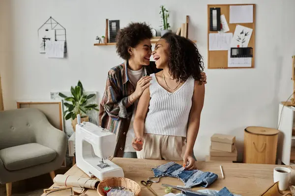 Coppia LGBT gioiosamente upcycling abbigliamento in un luminoso, spazio di lavoro artistico. — Stock Photo