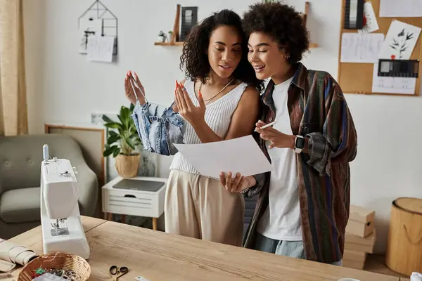 Coppia collabora gioiosamente su abbigliamento upcycling nel loro spazio di lavoro elegante casa. — Stock Photo