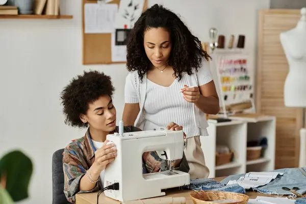Una pareja disfruta de un proyecto de ropa de bricolaje, transformando la tela en su vibrante espacio de trabajo. - foto de stock