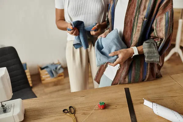 Una pareja transforma alegremente prendas viejas en nuevas creaciones. - foto de stock