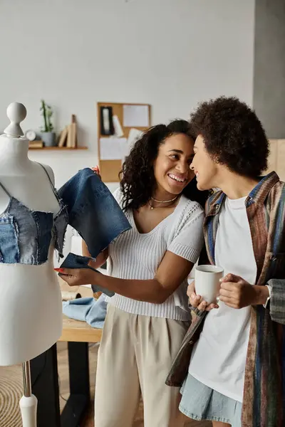 Two partners joyfully craft new outfits from old denim in a cozy workshop. — Stock Photo