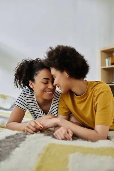 A joyful couple shares a tender embrace and laughter on a soft carpet. — Stock Photo
