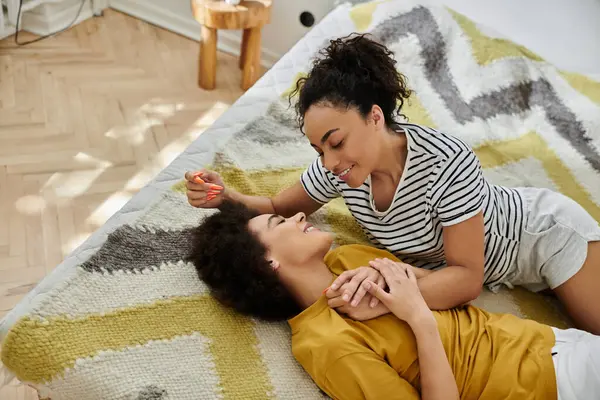 Two women share laughter and love on a warm, inviting blanket. — Stock Photo