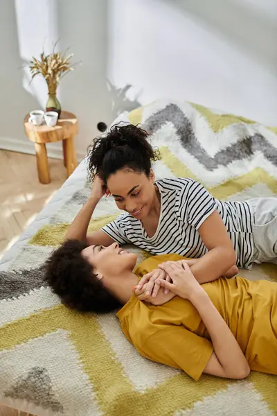 A loving couple shares a tender moment lying together on a vibrant rug. — Stock Photo