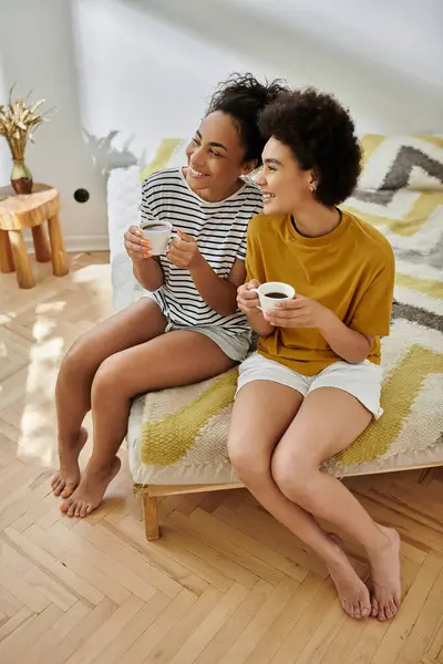 Due donne condividono risate e caffè in un ambiente familiare caldo e invitante. — Foto stock