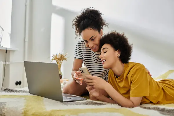 Two women share laughter and joy while looking at a phone together. — Stock Photo