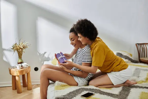 Un couple aimant partage joie et rire tout en déroulant un cadeau surprise ensemble. — Photo de stock