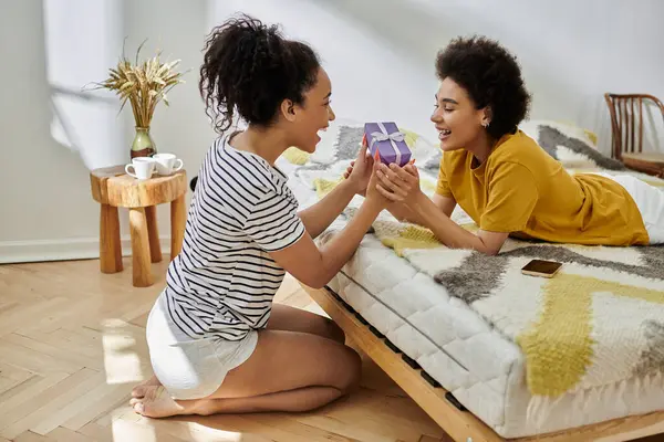 Two women exchange a heartfelt gift on their cozy bed. — Stock Photo