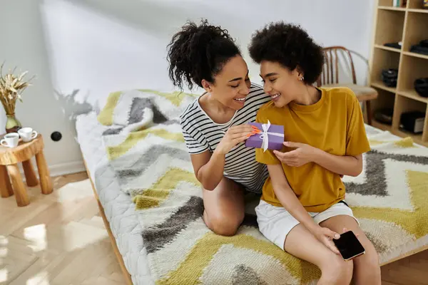 A joyful couple shares a sweet moment while unwrapping a surprise gift. — Stock Photo